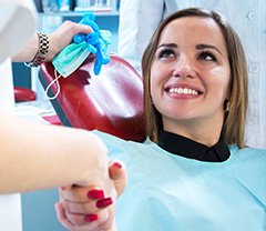Woman in dental chair shaking hands with dentist